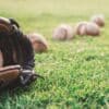 A close-up of a baseball glove with balls on a green field, symbolizing outdoor sports.