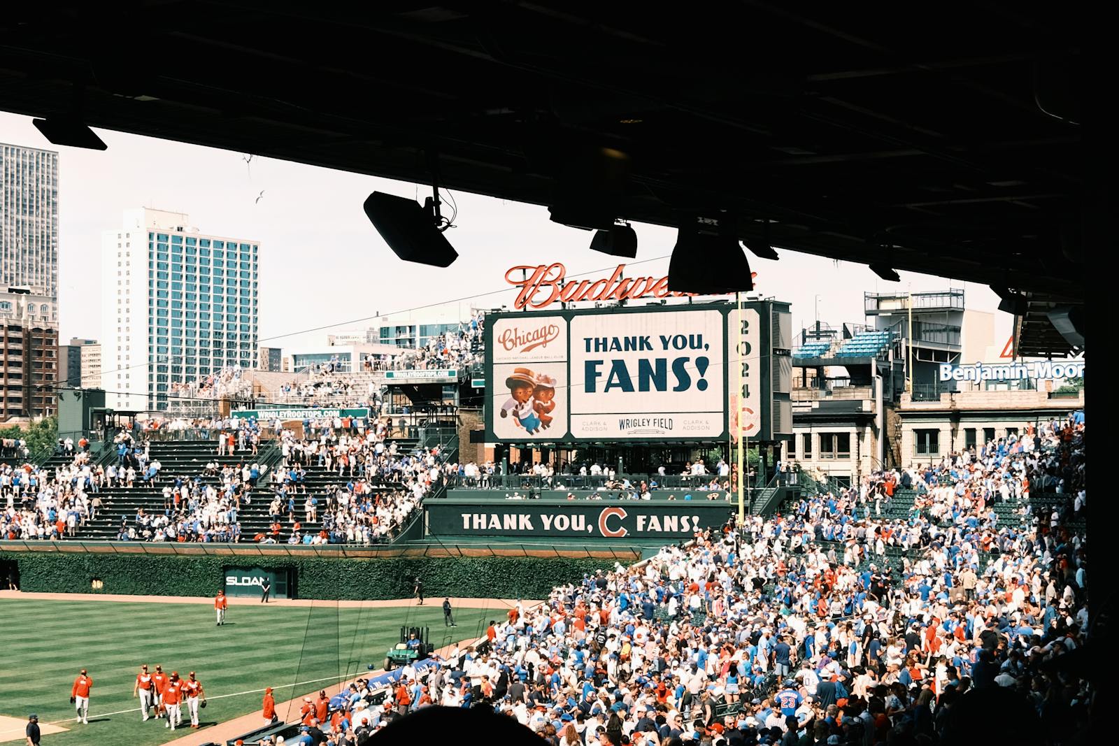 Crowd enjoying a baseball game at Wrigley Field, Chicago's iconic stadium, on a sunny day.