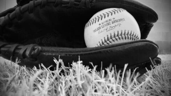 a black and white photo of a baseball in a baseball mitt