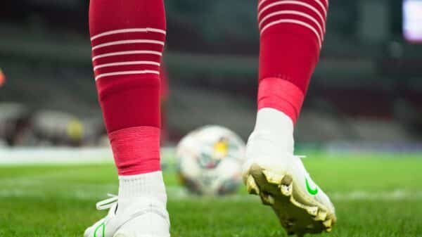 a close up of a soccer player's feet with a ball in the background
