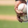 man holding two white baseballs